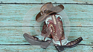 Cowboy boots and hat on a teal background