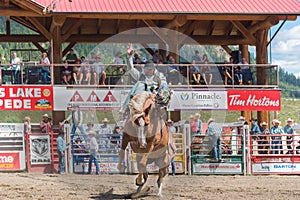 Cowboy on bucking horse during saddle bronc competition at rodeo