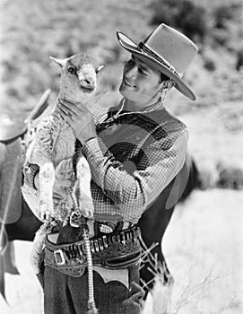 Cowboy carrying a lamb and smiling