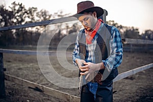 Cowboy checks revolver before gunfight on ranch