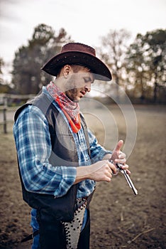 Cowboy checks revolver before gunfight on ranch