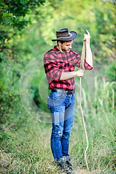 Cowboy at countryside. Man wearing hat hold rope. Ranch occupations. Lasso tool. American cowboy. Lasso tied wrapped