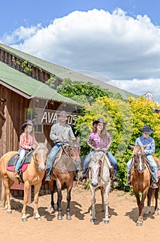 cowboy family of four on horses on background of