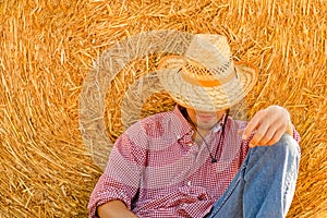 cowboy on a field near a haystack. Bales on the field with a happy man. Rest after a hard day