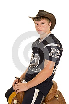 Cowboy in football jersey sitting on saddle