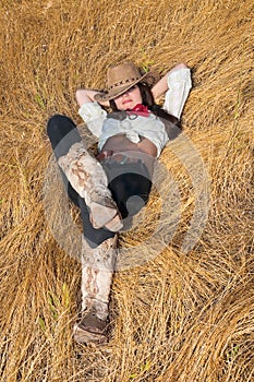 Cowboy girl lying in a field of grass