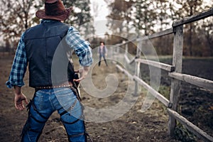 Cowboy with gun prepares to gunfight, back view