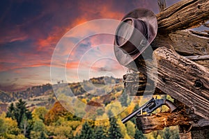 cowboy hat, airsoft gun on an abandoned cabin with a autumn background