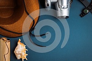 Cowboy hat, camera, compass, old paper scroll and seashell on a blue background