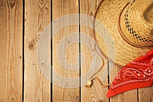 Cowboy hat with red bandanna on wooden rustic background.