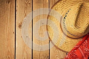 Cowboy hat on wooden vintage table with red bandanna for party invitation.