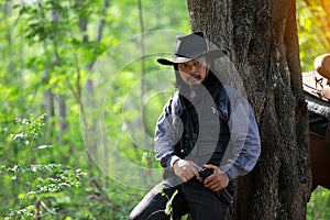 Cowboy on his horse walking through dust in the forest