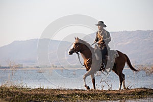 Cowboy on his horse walking through dust in the lake