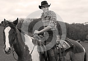 Cowboy on horseback, horse riding with chequered shirt and trees in background