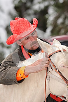 Cowboy hunter preparing white horse