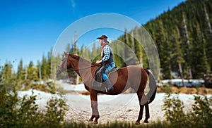 Cowboy in jeans and leather jacket riding a horse