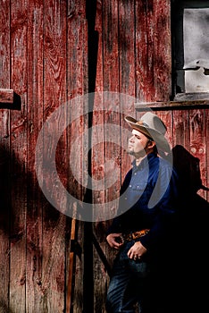 Cowboy Leaning on Barn Looking Up