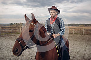 Cowboy in leather clothes riding a horse on farm