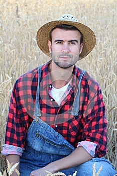 Cowboy man handsome and good looking with hat, overalls and plaid shirt in rural USA countryside. Male model in american western