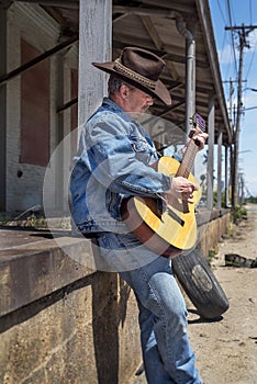 Cowboy playing acoustic guitar wearing jeans outdoors