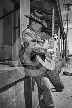 Cowboy playing acoustic guitar wearing jeans outdoors