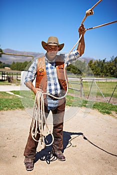 Cowboy, ranch and farmer in outdoor, sun and straps for wrangler and Texas lasso at stable. Mature man, wild west and