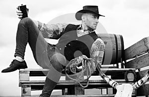 Cowboy on ranch. Handsome man in cowboy hat and retro vintage outfit. Guy drinking whiskey.