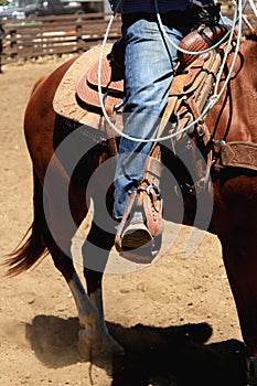 Cowboy riding a horse with the stirrup in front.