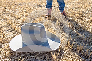 Cowboy standing near felt hat on wheat field