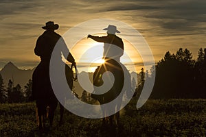 Cowboys riding across grassland early moring, British Colombia,