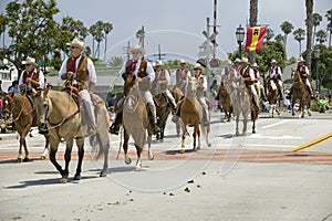 Cowboys riding down street on horseback during opening day parade down State Street, Santa Barbara, CA, Old Spanish Days Fiesta