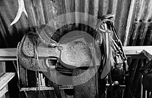 A cowboys saddle and tack hanging on a rail in the barn.