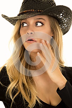 Cowgirl in black hand on face look to side