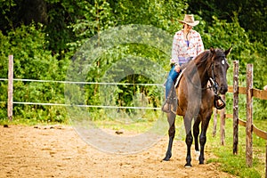 Cowgirl doing horse riding on countryside meadow