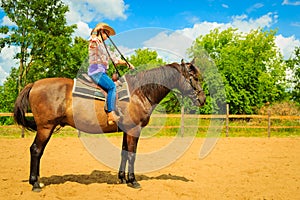 Cowgirl doing horse riding on countryside meadow