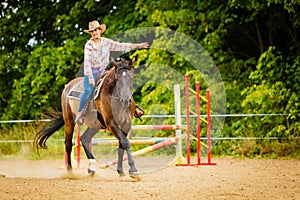 Cowgirl doing horse riding on countryside meadow