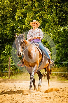 Cowgirl doing horse riding on countryside meadow