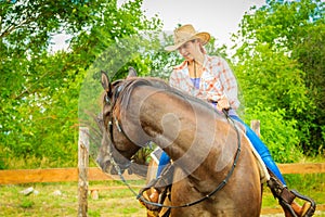 Cowgirl doing horse riding on countryside meadow