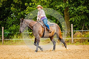 Cowgirl doing horse riding on countryside meadow