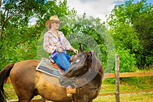 Cowgirl doing horse riding on countryside meadow