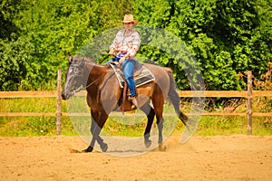 Cowgirl doing horse riding on countryside meadow