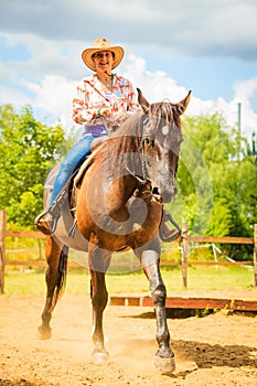 Cowgirl doing horse riding on countryside meadow