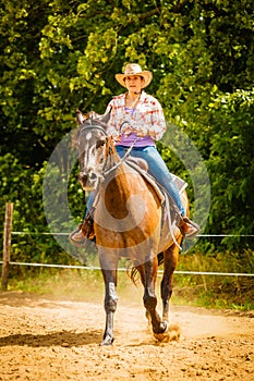 Cowgirl doing horse riding on countryside meadow