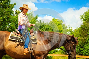 Cowgirl doing horse riding on countryside meadow