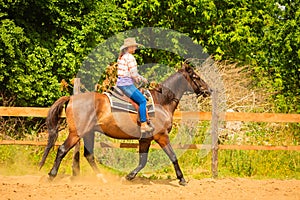 Cowgirl doing horse riding on countryside meadow