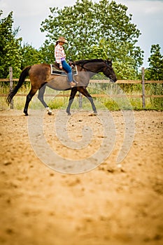 Cowgirl doing horse riding on countryside meadow