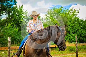 Cowgirl doing horse riding on countryside meadow