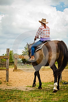 Cowgirl doing horse riding on countryside meadow