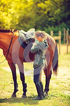 Cowgirl getting horse ready for ride on countryside