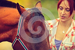 Cowgirl getting horse ready for ride on countryside